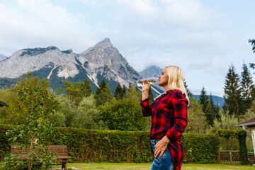 Fototapeta na wymiar Alps. A woman drinking water from a bottle and admiring the mountain scenery.