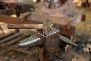 Hammer and blacksmith anvil at outdoor forge, workshop - close up, selective focus. Handmade, craftsmanship and blacksmithing concept