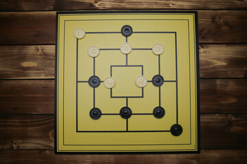 Top down view on gameboard with black and white pieces of strategy game for two people - nine men's...