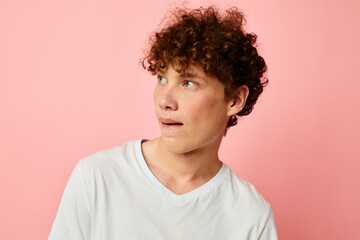 Fototapeta na wymiar portrait of a young curly man in white t-shirt casual wear emotions pink background unaltered