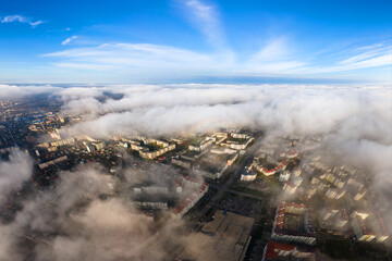 Top aerial view of fluffy white clouds over modern city with high rise buildings