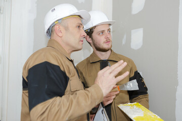 young apprentice with professional plasterer