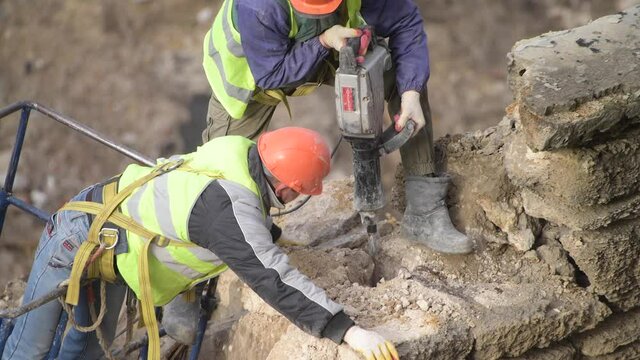 Demolition of old abandoned house, workman in orange helmet destroy wall with jackhammer. Deconstruction of living house. Urban Renewal 4k High quality video