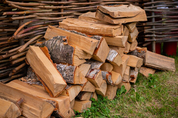 Stacked chopped triangle firewood for fireplace on ground - outdoor, summer time