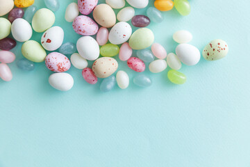 Happy Easter concept. Preparation for holiday. Easter candy chocolate eggs and jellybean sweets isolated on trendy pastel blue background. Simple minimalism flat lay top view copy space.