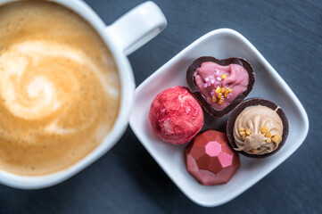Edle leckere Pralinen und ein frischer Kaffee Crema auf grauem Hintergrund