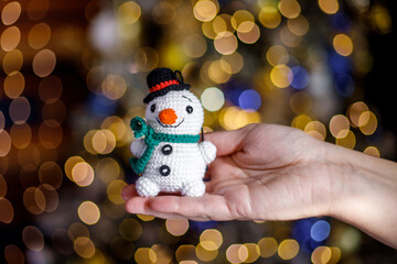 In the hands of a knitted toy for decorating a Christmas tree.