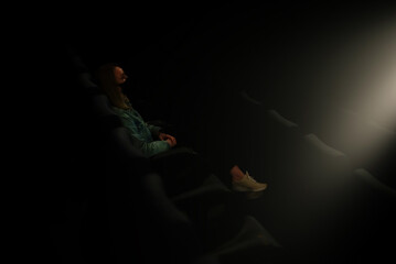 Naklejka na ściany i meble Woman in medical mask is watching movie in the cinema.