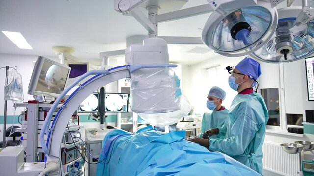 Two surgeons carry out the operation and look at the screen. Well-equipped surgery room in modern hospital.