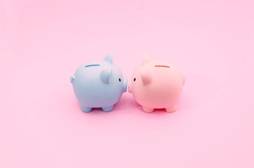 A blue and a pink piggy bank on pastel pink background. Valentines day creative concept. Love and money contemporary artistic design for advertisement or web banner.