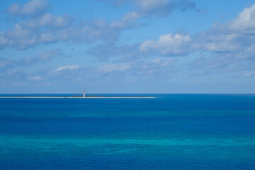 Lighthouse on the horizon, blue ocean and sky with white clouds