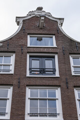Fototapeta na wymiar Close-up view details of colorful building with gable rooftop and hook along Prinsengracht canal in Amsterdam. Prinsengracht (Prince's Canal) named after Prince of Orange. Amsterdam, the Netherlands.
