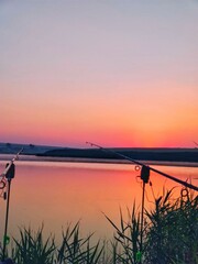 The photo shows the sunset while fishing with rods