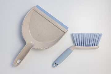Garbage bin scoop set. Plastic gray and blue dustpan and hand brush on white background. Home cleaning, domestic chores concept. Top view, copy space