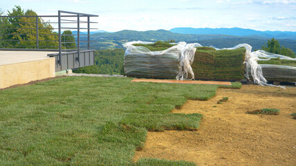 Two unpacked stacks of grass patches lie next to balcony and unfinished backyard - obrazy, fototapety, plakaty