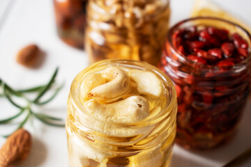 different nuts in jars in honey on a wooden table