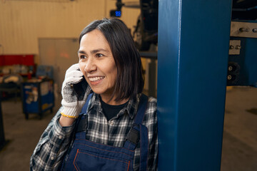 Excited female mechanic chatting on phone during break from work