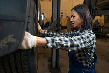 Hard-working female mechanic dealing with car wheels