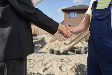 Two people shaking hands on construction area
