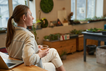Creative pretty woman enjoying hot drink in the studio