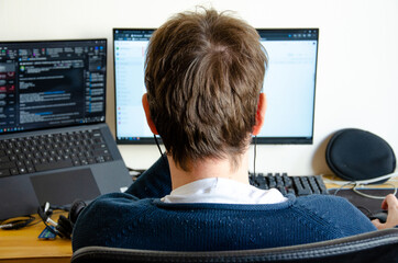 a man working on computer monitor seen from back