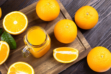 Fresh orange juice in a glass on a wooden background. Fresh Orange fruits with green leaves. Healthy vegan food. Vitamins food.Ripe oranges.Flat lay.