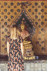 Blonde Frau steht vor Buddha Statue in Tempel in Bangkok, Thailand