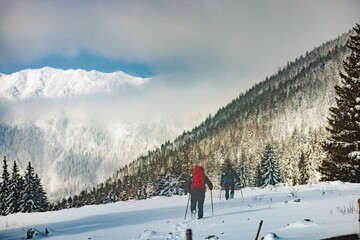 People hiking heading into the mountains, carefully if weather is winter. Pack extra clothing, food, and water if you want to go off on your own. Winter hiking scene people exploring winter mountains