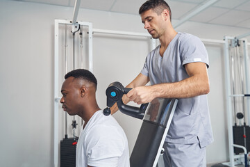 Concentrated physical therapist performing percussive therapy session