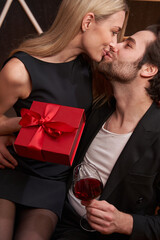 Female holding present and kissing a man
