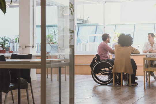 Latino Adult Man In Wheelchair In Eco Office For Business Meeting