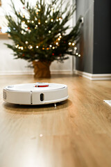 Smart home. Robot vacuum cleaner performs automatic cleaning. Cleans the parquet from Christmas tree needles after the new year. cleans near the Christmas tree after the holidays.
