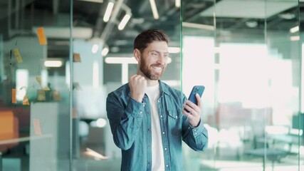 happy business man freelancer, employee, worker celebrate mobile win excited overjoyed lucky winner receive good news in message use smartphone rejoice bet financial success victory in office. indoor