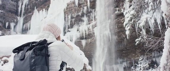 Hiker woman flask in hands hiking travel at winter Alps waterfall