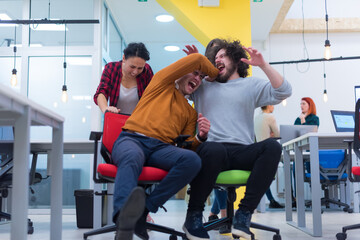 Young business people ride chairs in the office