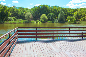 Observation deck with wooden balustrade at the lake . Pond on a summer day