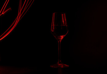 Champagne glass illuminated with red light painting on black background