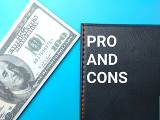 Banknote and notebook with word PRO AND CONS on a blue background. Business concept.