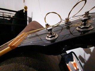 Tuning peg on acoustic guitar headstock with strings. Close up photo
