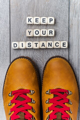 Legs in boots with red laces on the gray floor in front of the inscription - KEEP YOUR DISTANCE