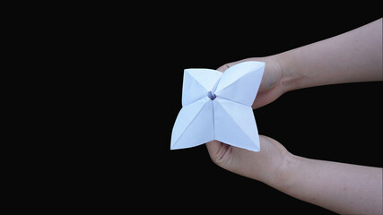 Hand holding fortune telling paper isolated on a black background with clipping path