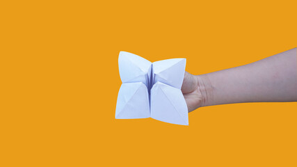 Hand holding fortune telling paper isolated on a orange background with clipping path