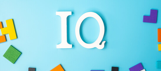 IQ text with colorful wood puzzle pieces, geometric shape block on blue background. Concept of intelligence quotient and logic thinking - obrazy, fototapety, plakaty