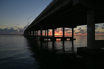 Rickenbacker Causeway bridge silhouetted against sunrise in Miami, Florida on calm winter morning.