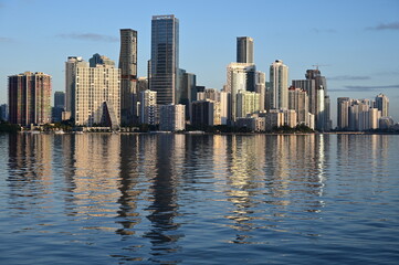 Fototapeta na wymiar City of Miami skyline reflected on tranquil water of Bisvcayne Bay in early morning light on calm clear winter day.