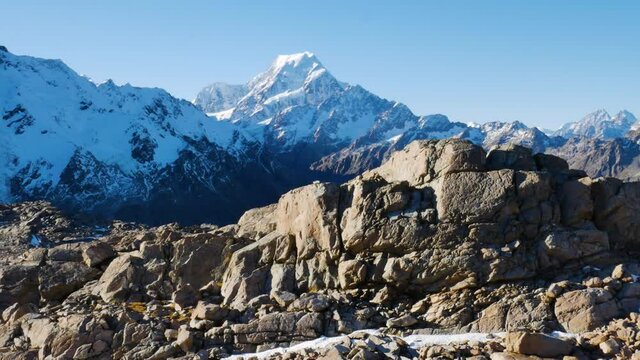 Panorama shot of massive mountains covered with snow during sunlight at Mueller Hut Route