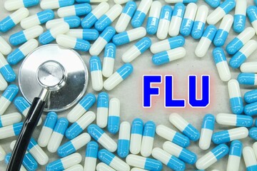 stethoscope and blue and white medicine with the word FLU. medical concept