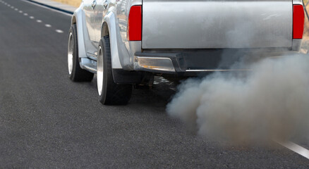 Air pollution from diesel vehicle exhaust pipe on road.