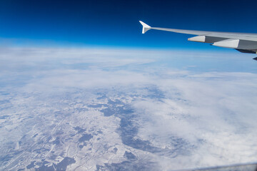 Fototapeta na wymiar Airplane Window View Wing Over Snowy Landscape