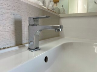Close up steel hot and cold faucet at the washbasin in bathroom
